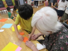 ７月の保育園交流会の様子です。園児と一緒に折り紙でコマを作りました。