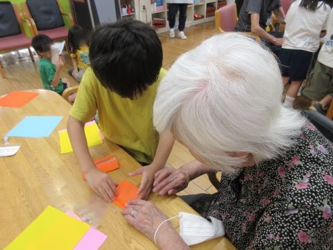 ７月の保育園交流会の様子です。園児と一緒に折り紙でコマを作りました。